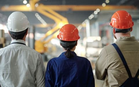 A back picture of three architects standing in a workstation.