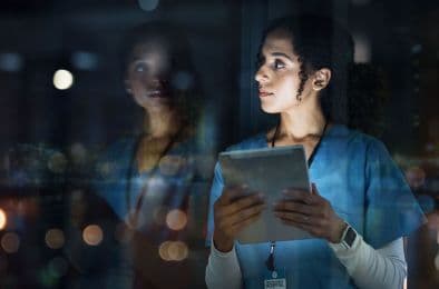 A picture of a nurse holding a tablet and looking outside.